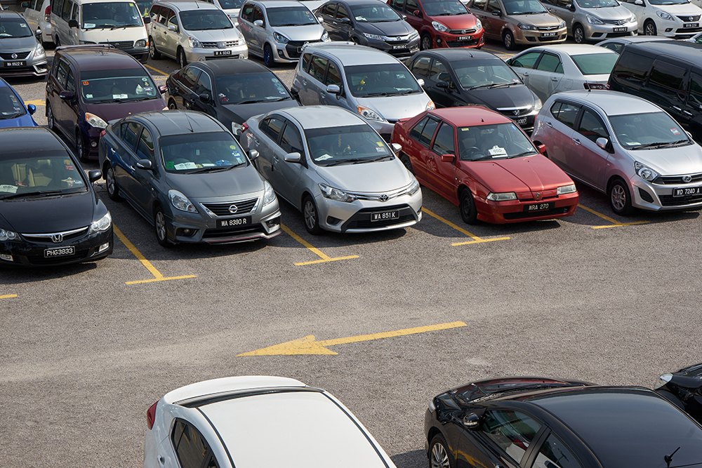 Rows of the number of cars parked in a public parking lots with asphalt paving issues